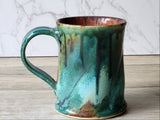 Side view of handmade pottery mug with teal green glaze and rust interior, Buxton Pottery