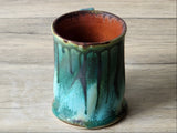 Rustic handmade pottery mug with curved handle and layered green glaze