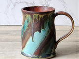 Handmade ceramic coffee mug with turquoise, green and copper glaze drips, side handle view