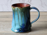 Unique handmade mug with green teal glaze and reddish brown rim detail