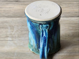 under side of glossy green and rust glazed ceramic coffee mug on wooden surface
