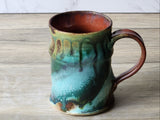 Artisan ceramic mug close-up showing drip glaze detail and flared rim