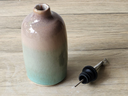 Close-up of green and brown glazed ceramic oil bottle showing glossy finish and colour variation