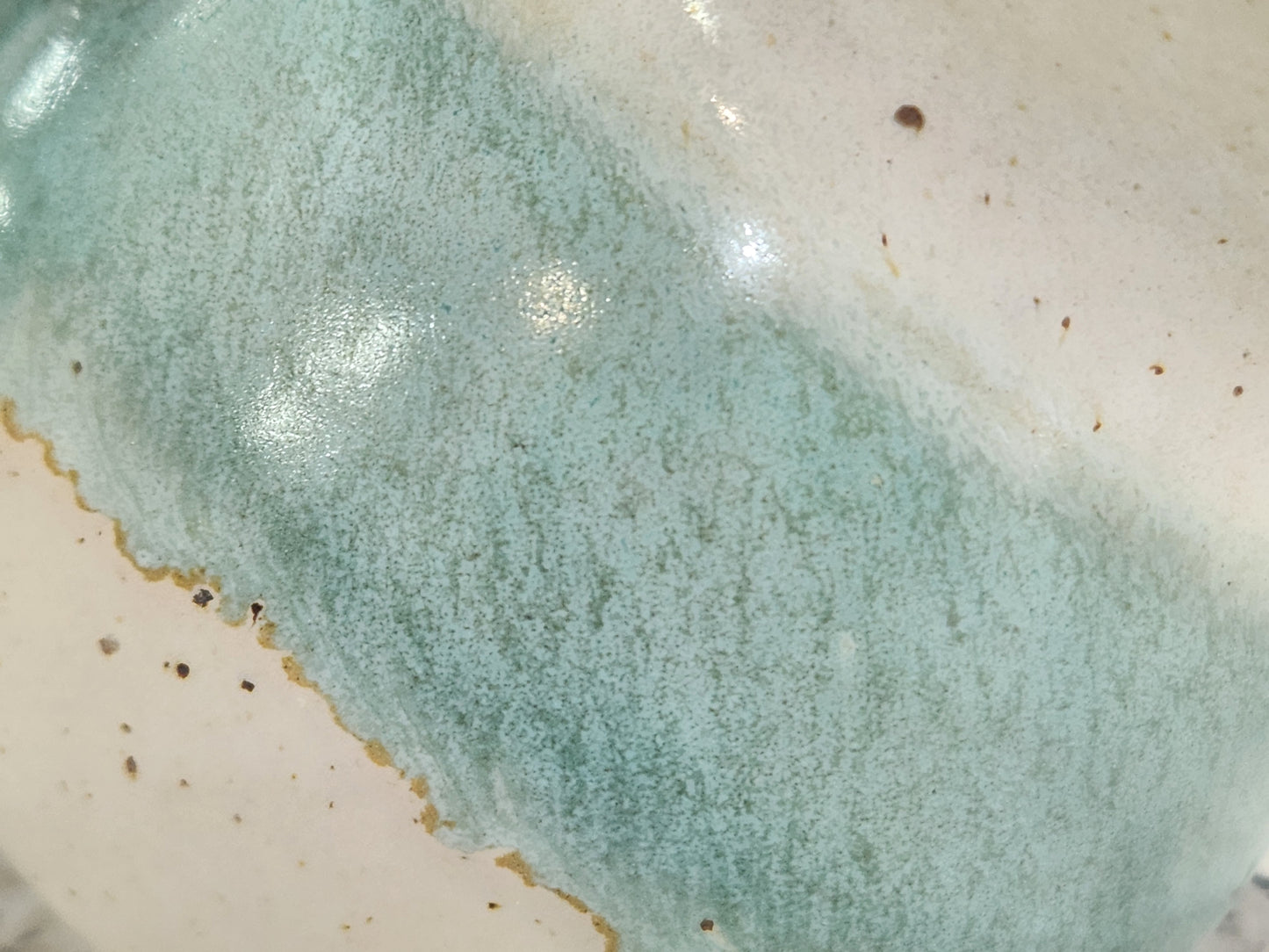 Close-up of aqua and cream glaze on a handmade ceramic salt pig