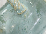 Close-up of soft green speckled glaze on a handmade ceramic salt pig