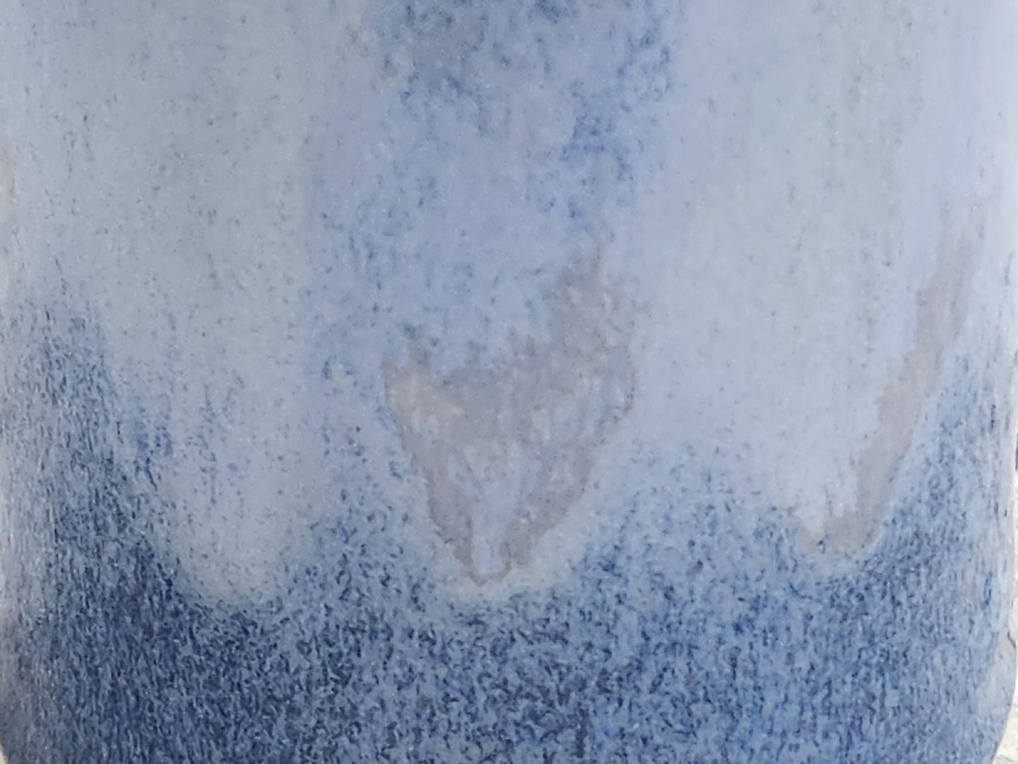 Close up of the mottled blue glaze of a small bud vase