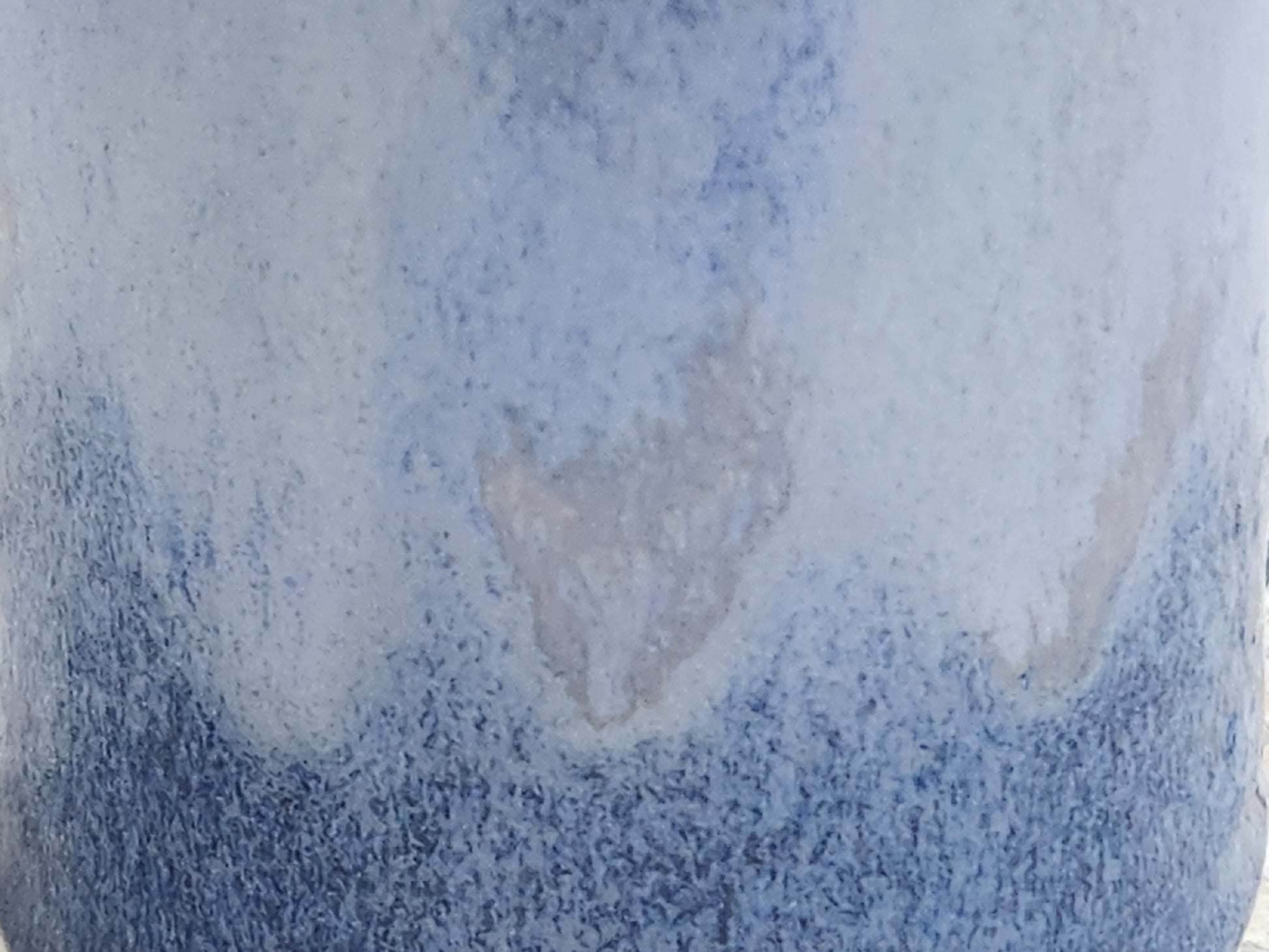 Close up of the mottled blue glaze of a small bud vase