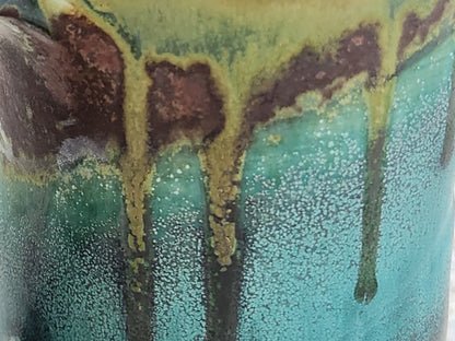 Close-up of flowing turquoise, green and earthy brown reactive glaze on a handmade Bush Creek Earth ceramic mug.