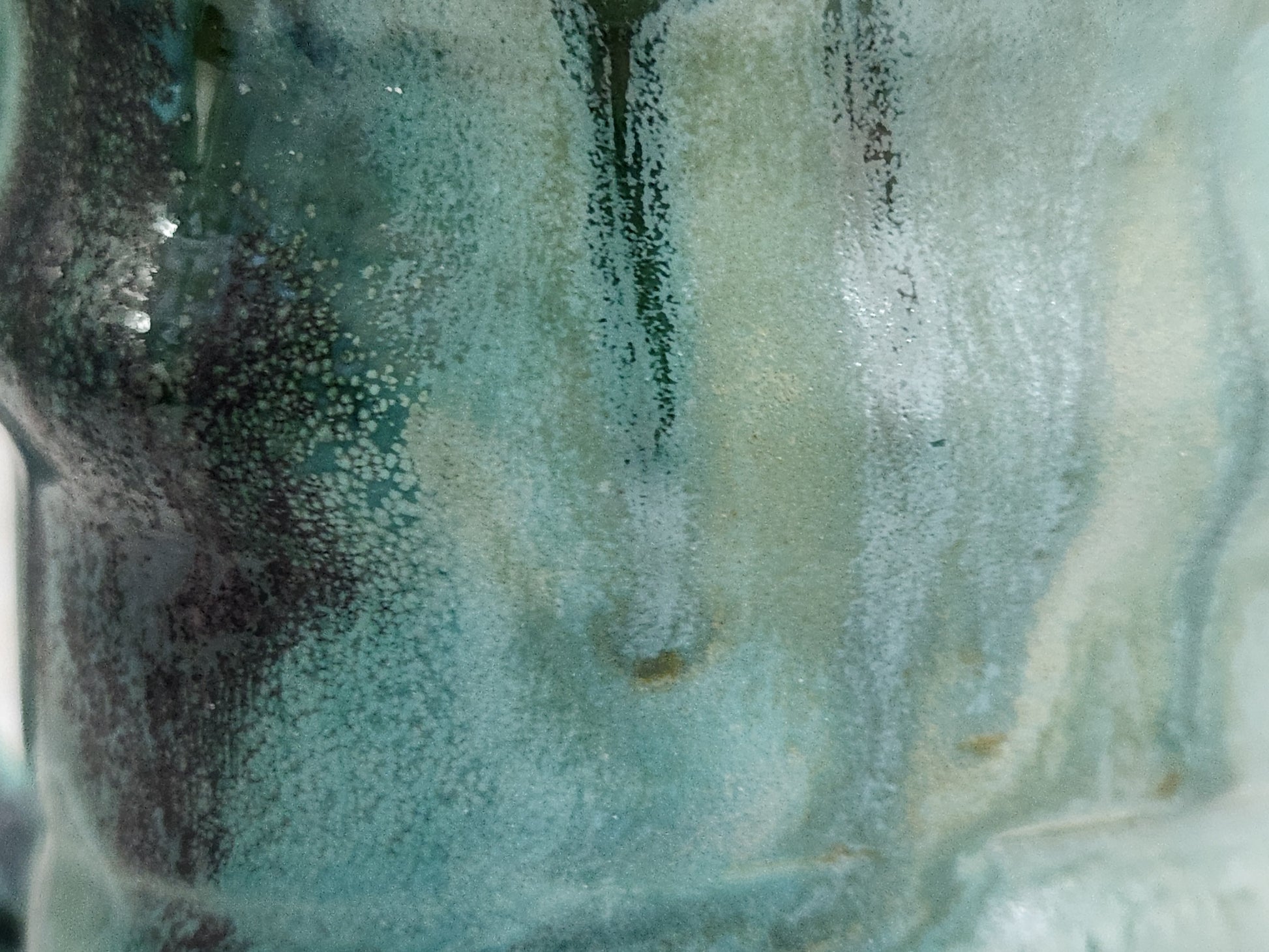 Close-up of handmade pottery mug showing turquoise, green and deep earthy Bush Creek glaze movement