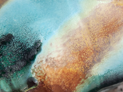 Close-up of handmade pottery mug showing turquoise, terracotta, green and deep earthy glaze movement