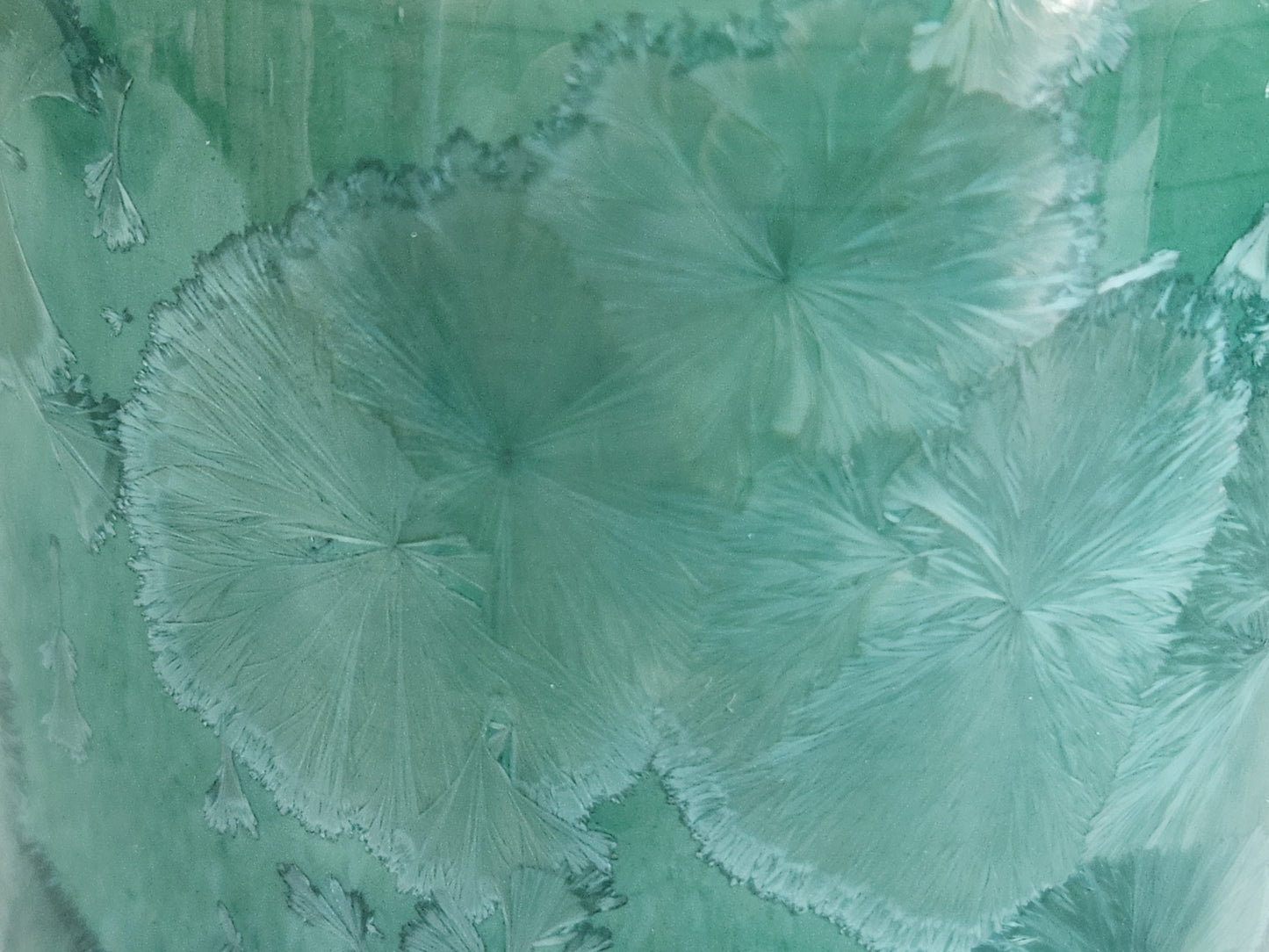 Close-up of pale crystal patterns on a green porcelain vase