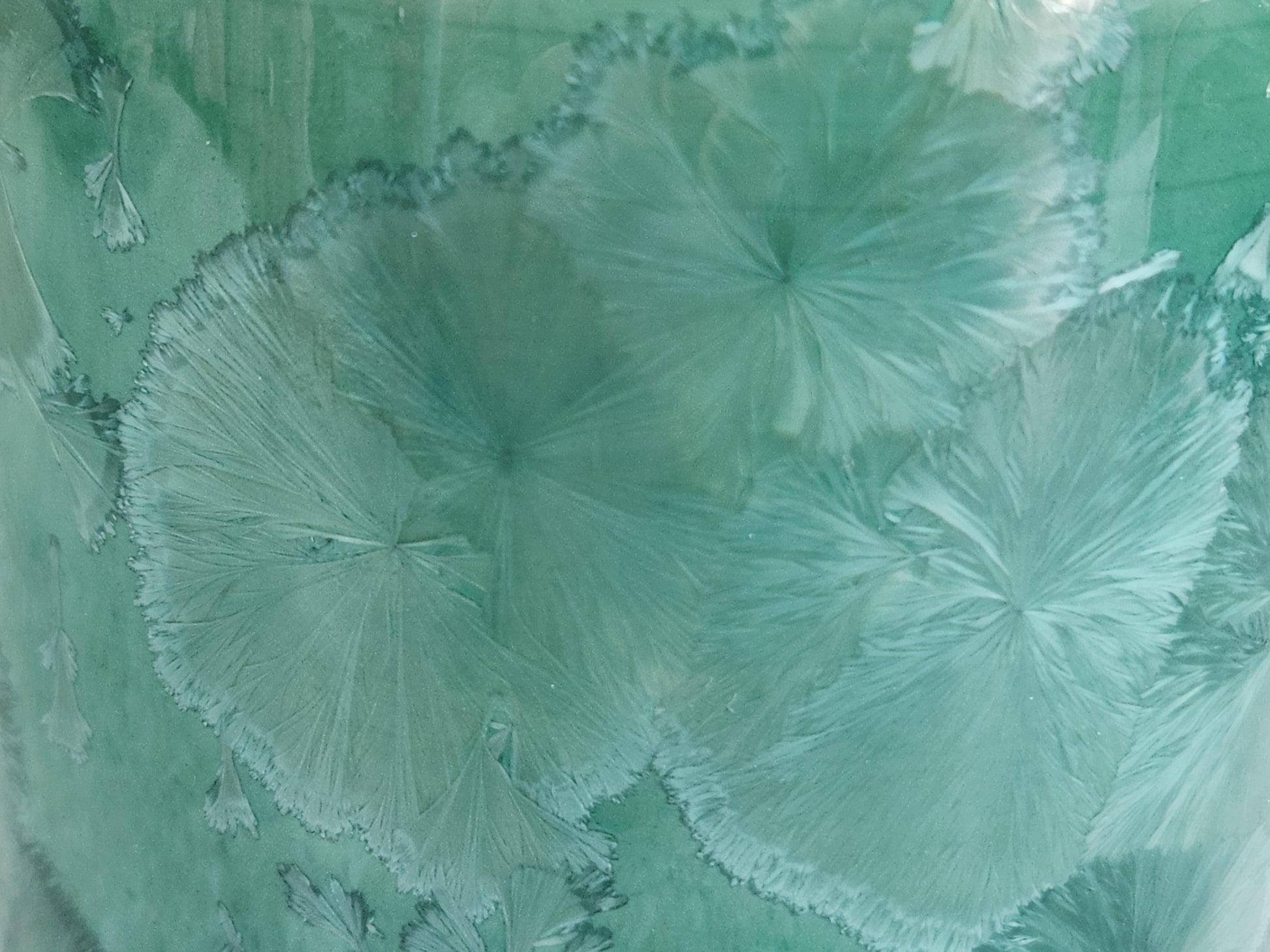 Close-up of pale crystal patterns on a green porcelain vase