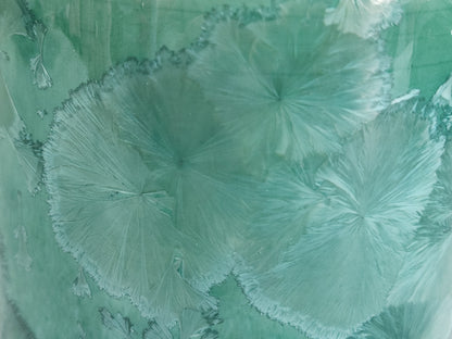 Close-up of pale crystal patterns on a green porcelain vase
