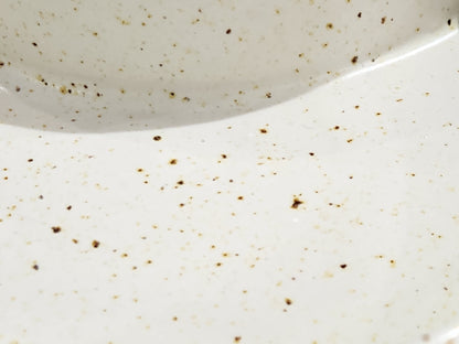 Close-up of speckled cream glaze on handmade ceramic chip and dip bowl with sauce compartment