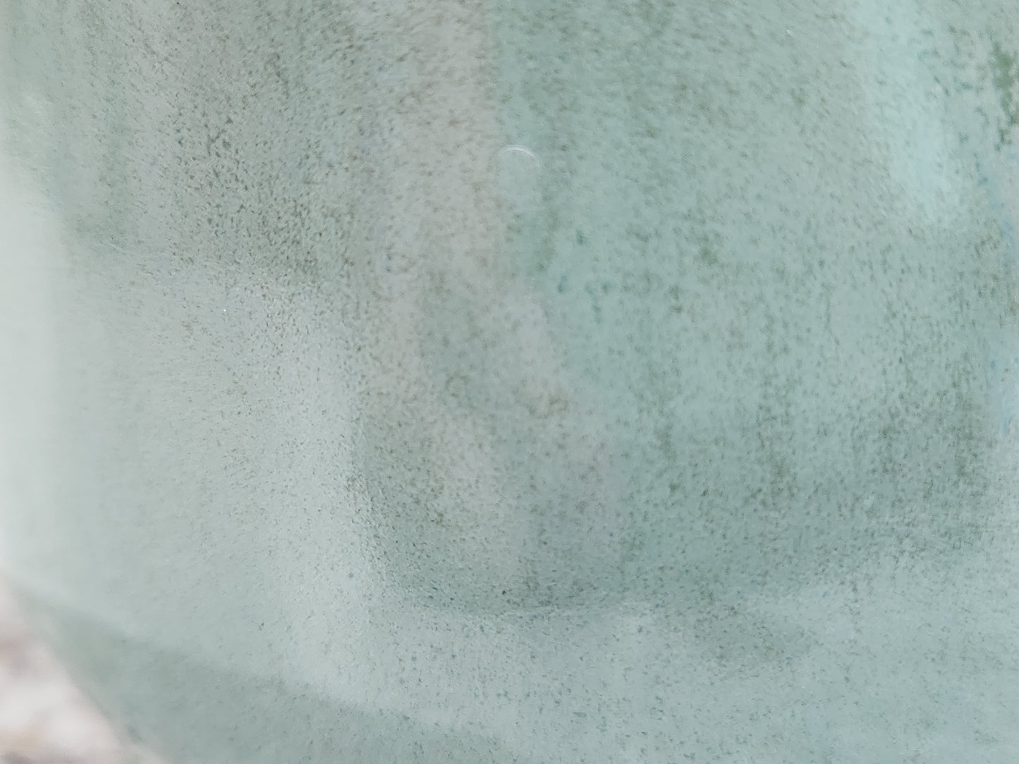 Close-up of handmade pottery sugar bowl showing soft seafoam green glaze and glossy surface variation