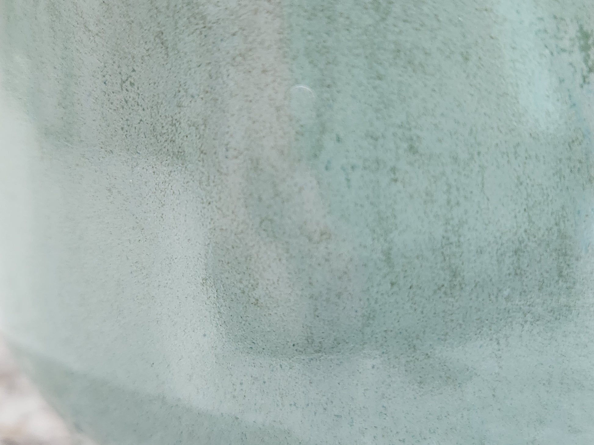 Close-up of handmade pottery sugar bowl showing soft seafoam green glaze and glossy surface variation
