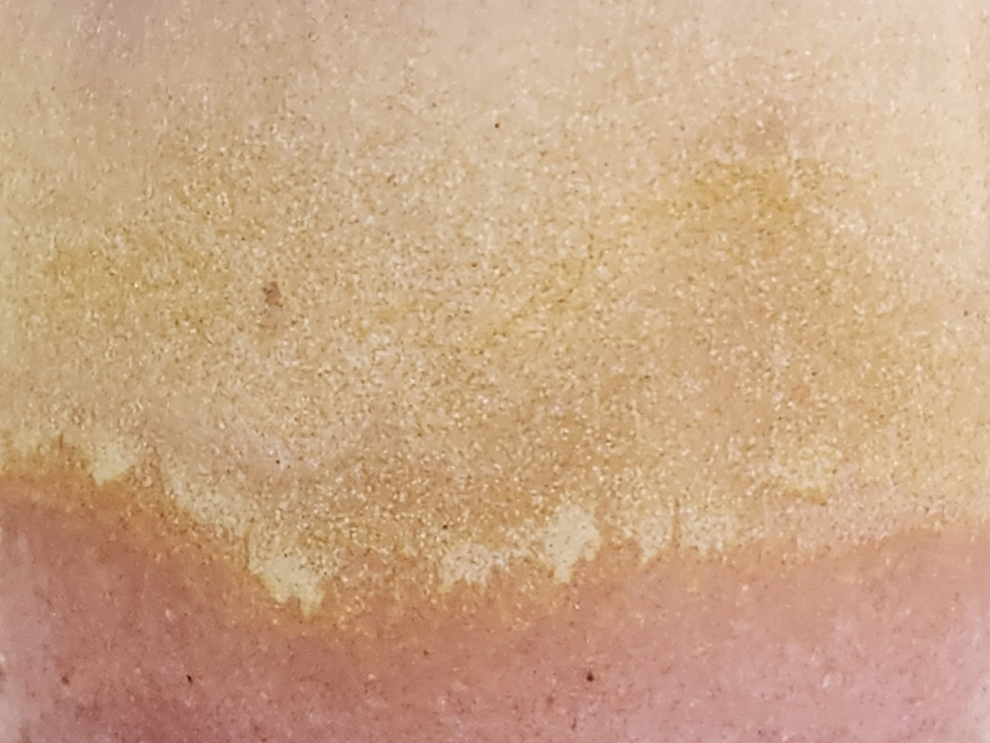 Close-up of soft pink and creamy oatmeal glaze on handmade stoneware mug