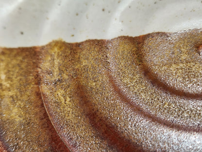 Close-up of cream and brown glaze on handmade ceramic spoon rest