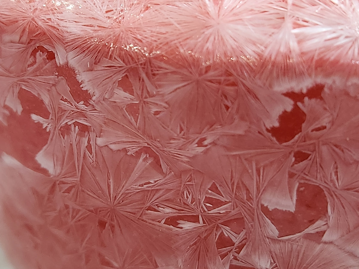 Close up of white crystalline glaze over red porcelain vase