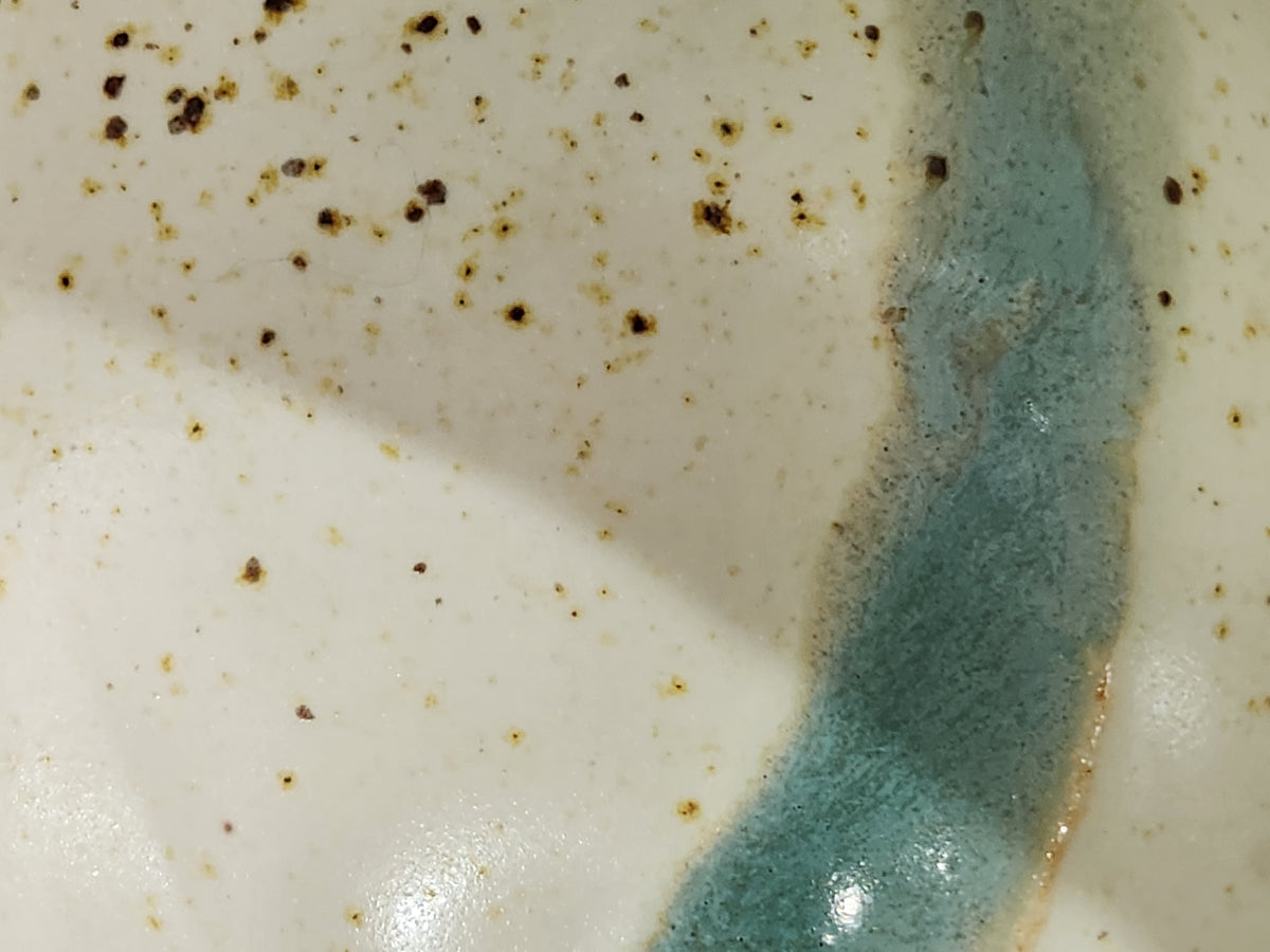 Close-up of the cream and muted blue-green glaze inside a handmade Buxton Pottery bowl.