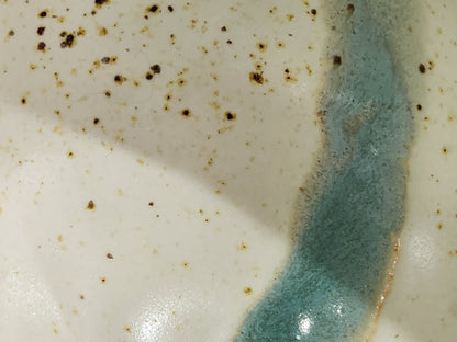 Close-up of the cream and muted blue-green glaze inside a handmade Buxton Pottery bowl.
