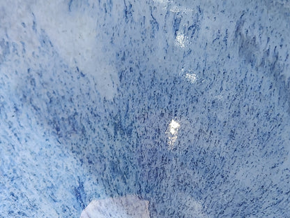 Close-up of fine dark blue glaze streaks across a handmade pottery bowl.