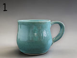 Small green handmade pottery mug with rounded shape