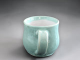 Green ceramic cup with curved handle and rounded form