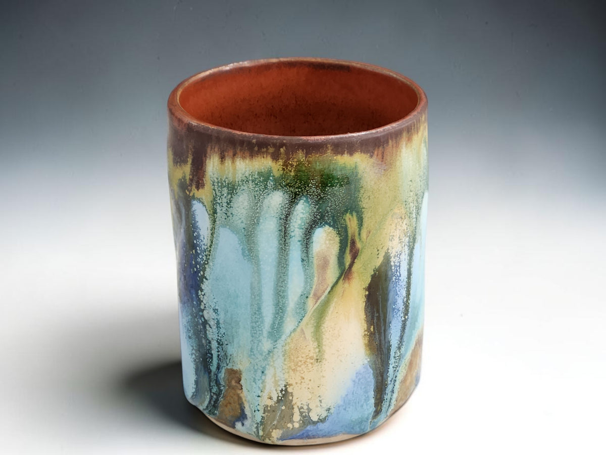 Handmade pottery tumbler showing unique blue green ochre and brown glaze pattern
