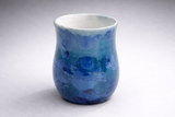 Handmade blue crystalline glaze mug on grey studio background