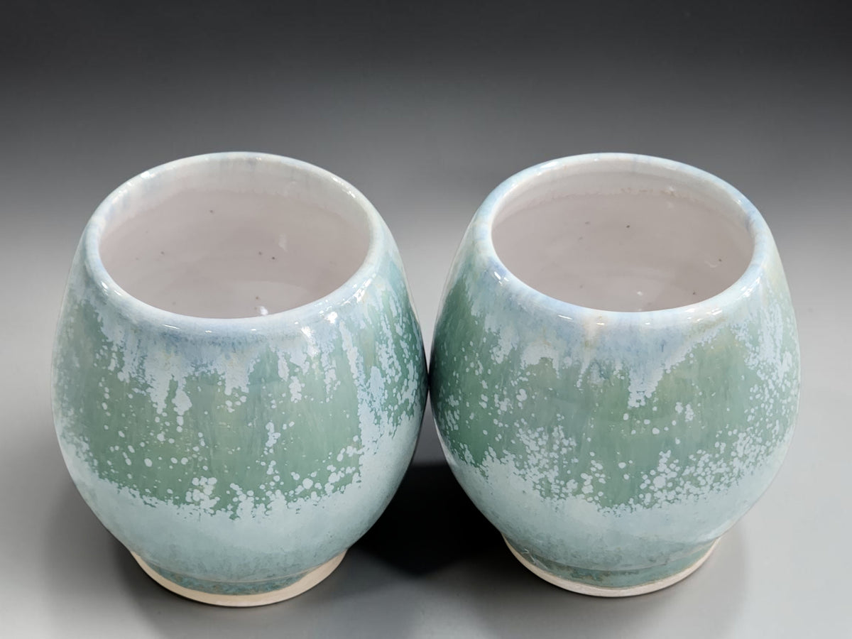 Handmade pottery whisky sippers with white interiors and pale green speckled glaze