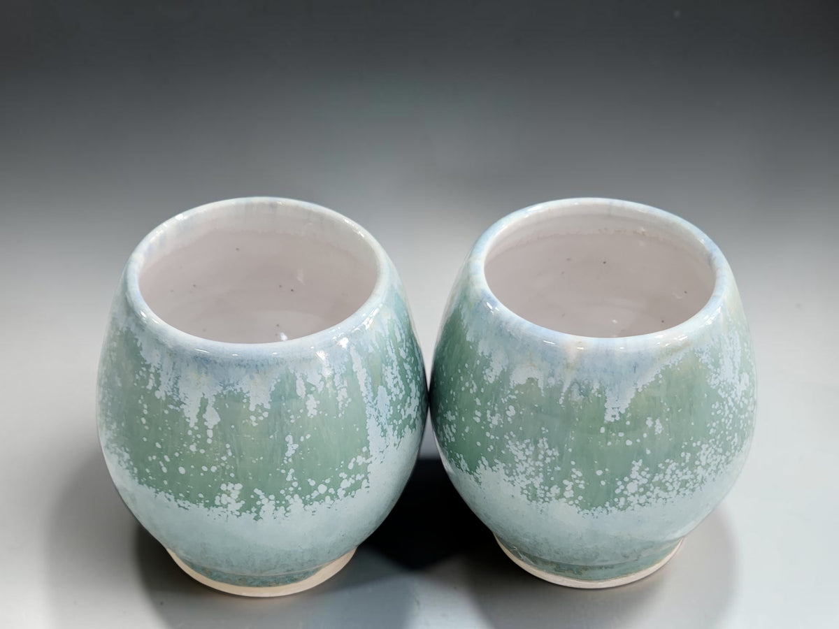 Small ceramic whisky cups with rounded shape and unglazed clay foot rings
