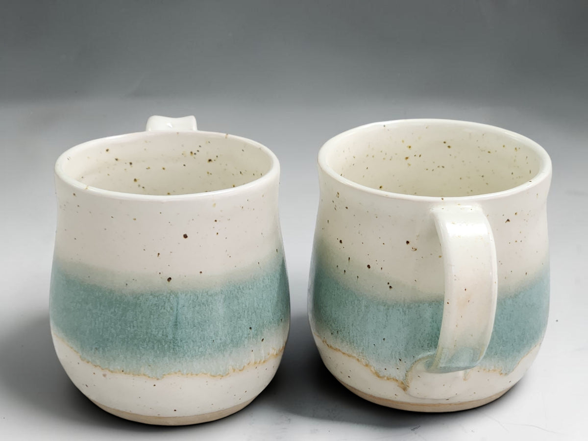 Handmade ceramic mug with layered speckled cream and green glaze tones