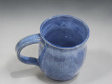 Blue handmade ceramic mug with French press on wooden kitchen bench
