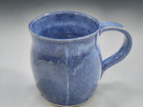 Handmade blue pottery mug with rounded handle on studio grey backdrop