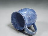 Handmade pottery coffee mug in variegated blue glaze on grey backdrop