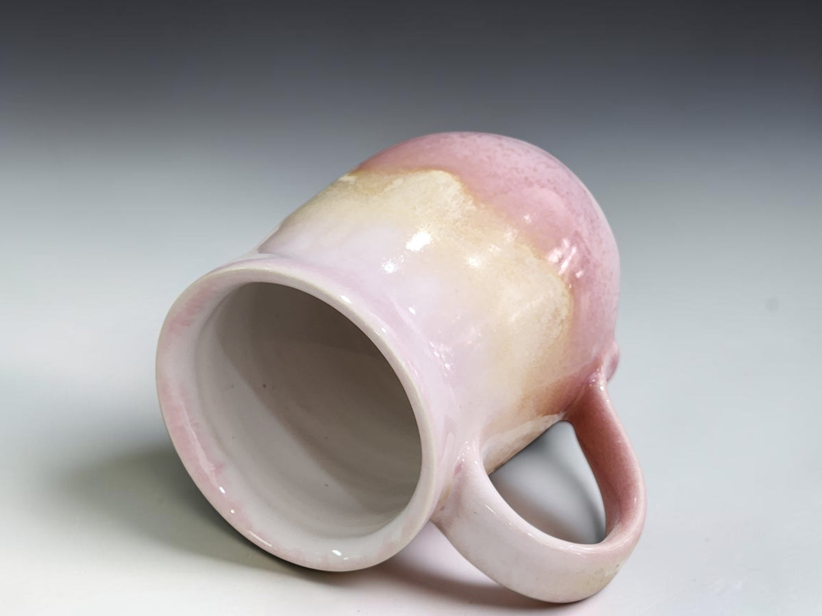 Handmade pink pottery mug with creamy oatmeal cascading glaze