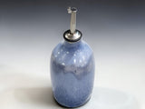 Handcrafted ceramic olive oil bottle in soft blue glaze with rustic kitchen styling