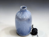 Blue glazed stoneware olive oil dispenser with stainless steel spout on a kitchen countertop