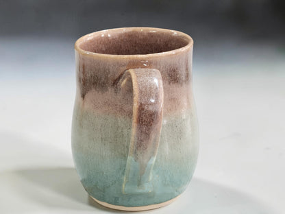 Spearmint green pottery mug with warm oatmeal glaze detail