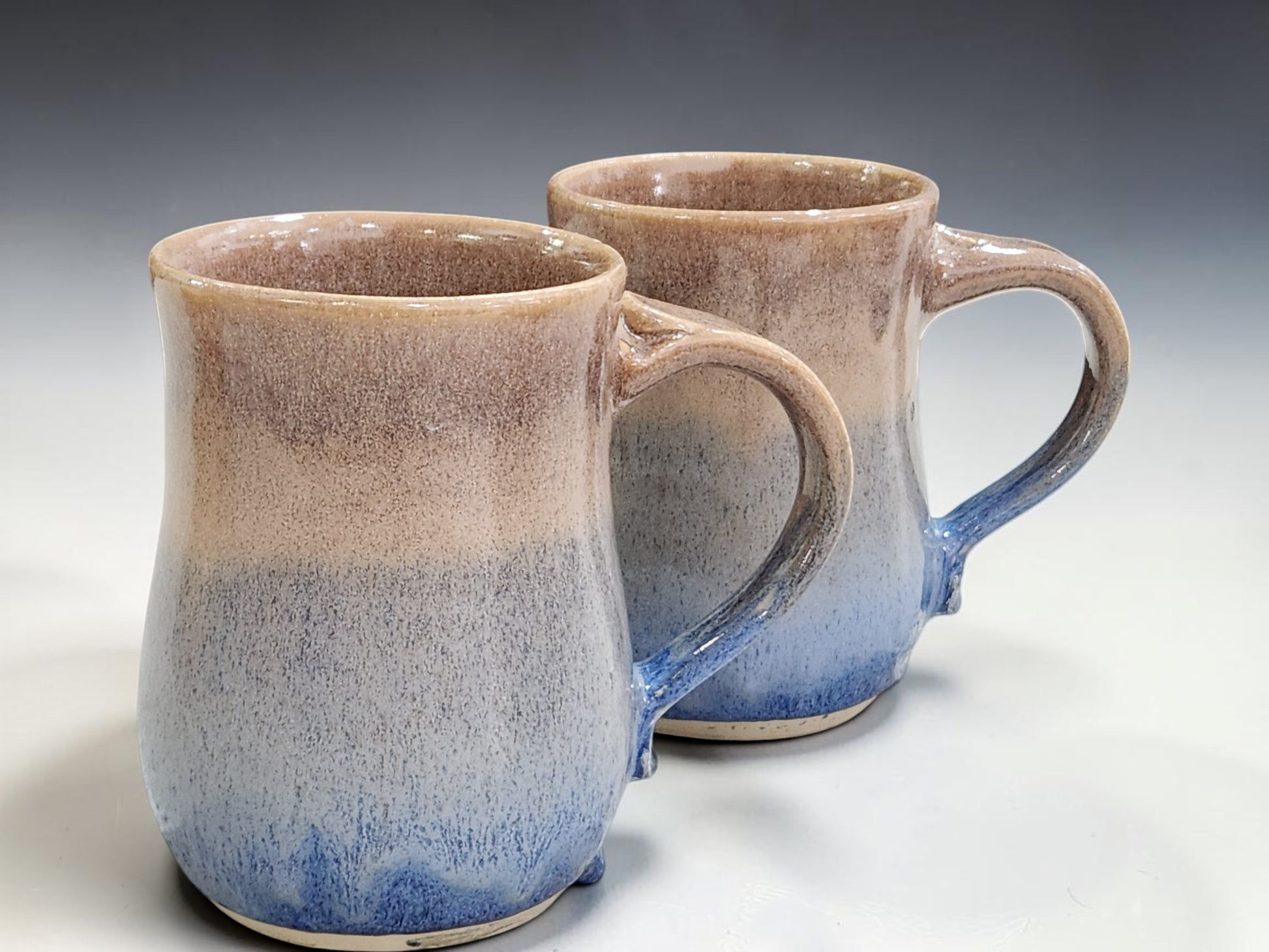Wheel-thrown stoneware mugs with glossy blue base and oatmeal brown upper glaze