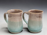 Pair of wheel thrown stoneware coffee mugs with soft oatmeal and blue glaze