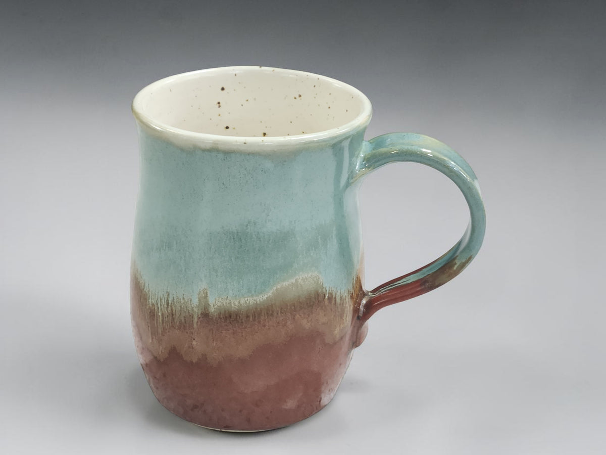 Handmade ceramic mug with green glaze and warm brown base