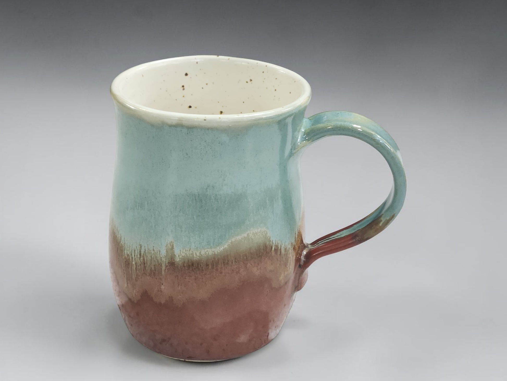 Handmade ceramic mug with green glaze and warm brown base