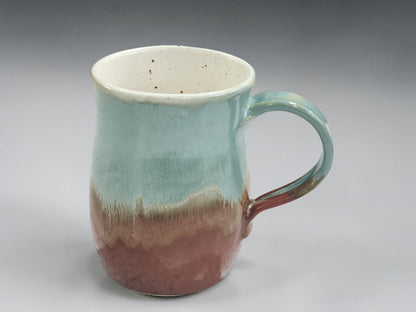 Handmade ceramic mug with green glaze and warm brown base