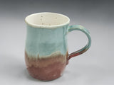 Handmade ceramic mug with green glaze and warm brown base