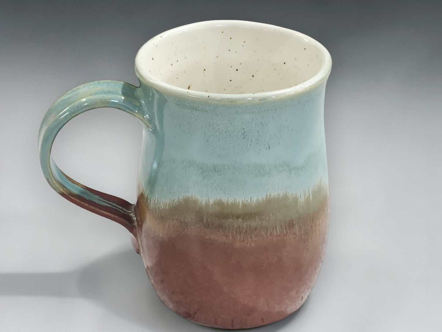 Green and brown handmade ceramic mug on grey background