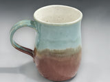 Green and brown handmade ceramic mug on grey background