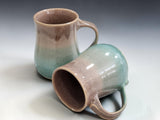 Two handmade ceramic mugs with glossy oatmeal and soft blue reactive glaze