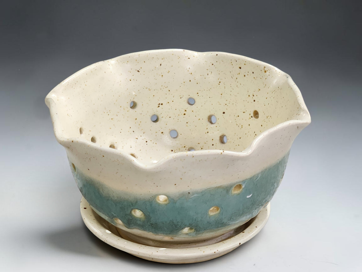 Pottery berry bowl with drainage holes and matching saucer in cream and aqua glaze